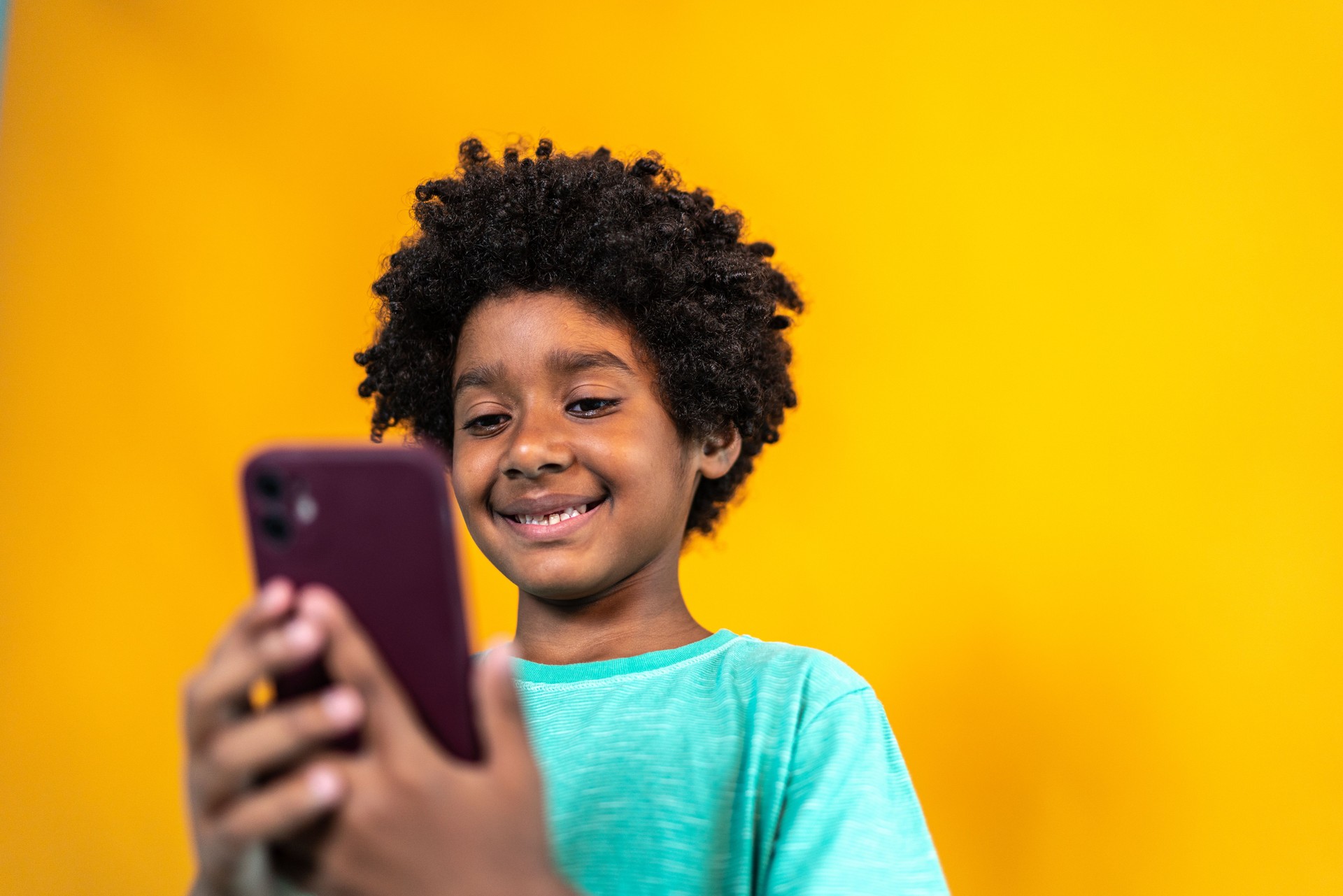 Boy using mobile phone on a yellow background